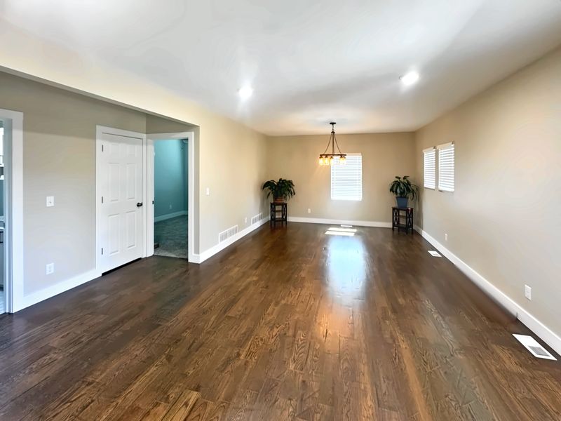Open living and dining room with dark hardwood floors, white trim and doors, and recessed lighting