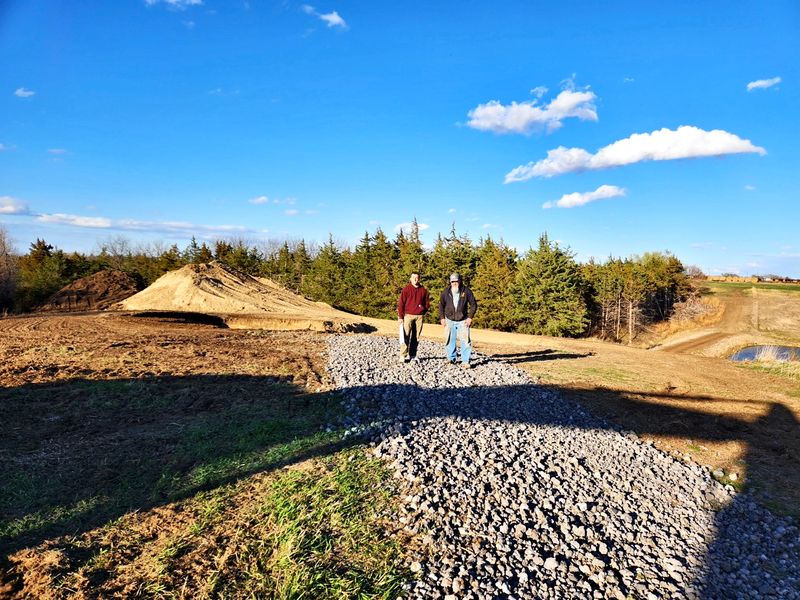 Gravel drive and site prep on a new home lot under a blue sky