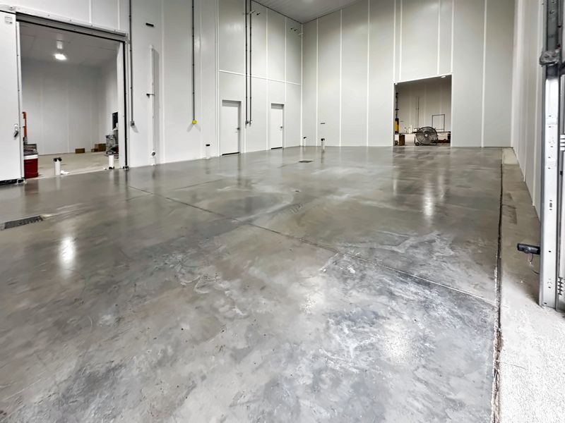 Clean shop building interior with white steel liner panels and a polished concrete floor